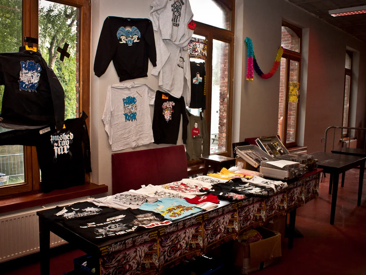 A picture of a store. On this table there are different type of clothes and boxes. Clothes are on...