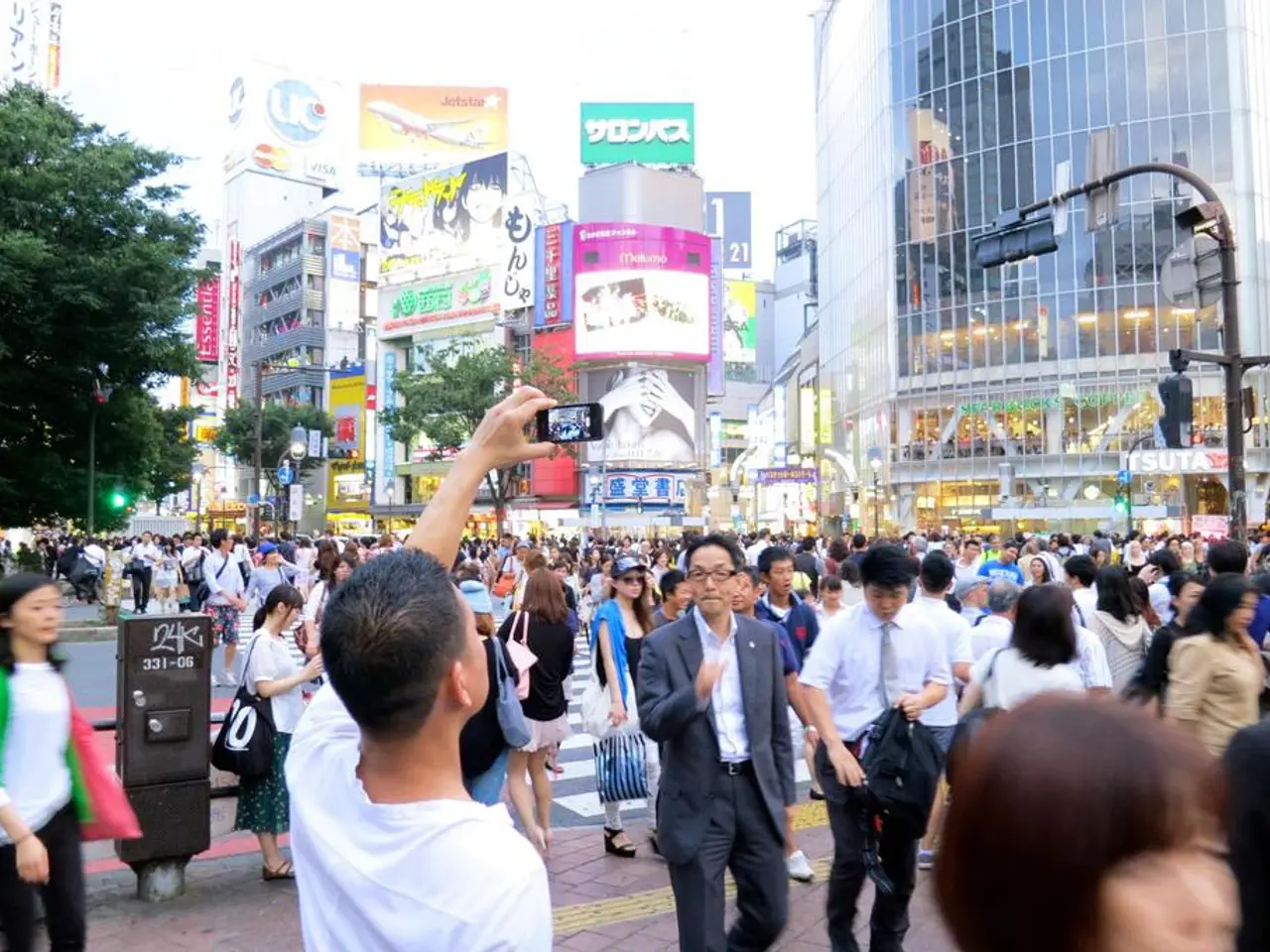 In this image I see number of people who are on the path and I see that this man is holding a...
