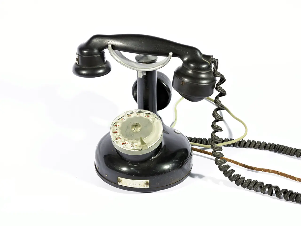 In this picture there is a black color telephone and there are numbers behind the glass and there...