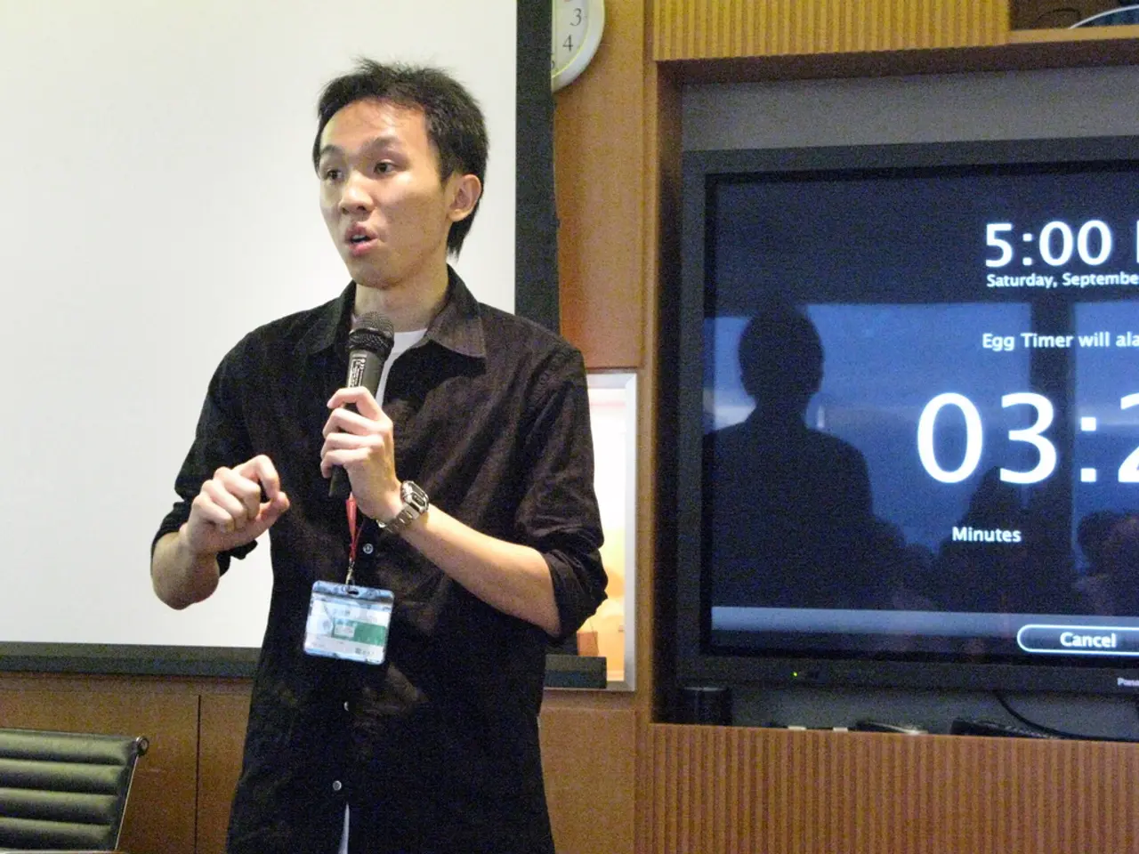 There is a man standing and holding a microphone and talking and wore tag,behind this man we can...