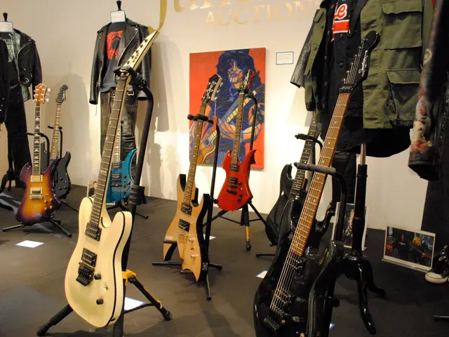 There are many guitars placed on stand. There are jackets on hangers. At the wall there are...