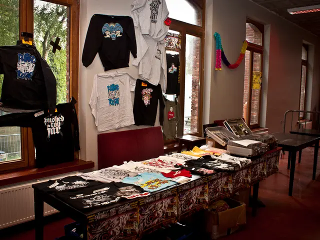 A picture of a store. On this table there are different type of clothes and boxes. Clothes are on...