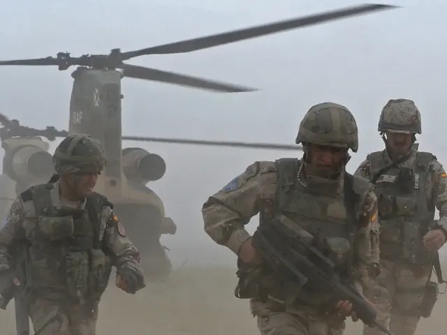 In this picture there are three persons holding the guns and running. At the back there is a...