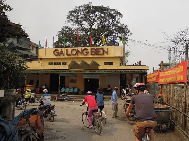 People are passing by a building on cycles and few bikes.
