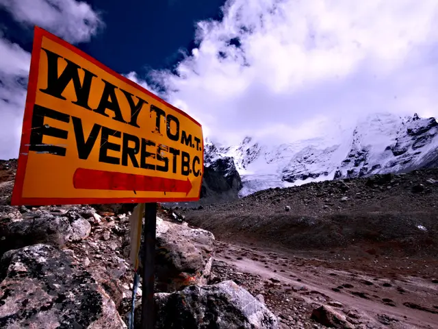 In this image we can see board with some text. In the background of the image there are mountains...