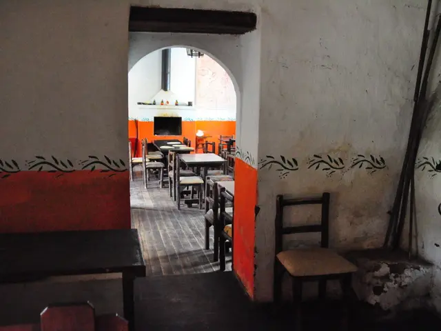 In the image we can see there are tables and chairs kept on the floor and there is a tv on the...